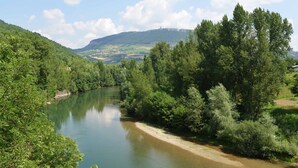 Ein Fluss, umgeben von dichtem Grün und Hügeln.
