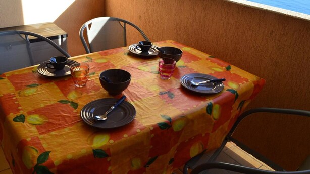 A table set with plates, bowls, and glasses, overlooking a scenic view of the sea. - Studio cabin Banyuls 4 pers, sea view, parking, WiFi (Banyuls-sur-Mer)