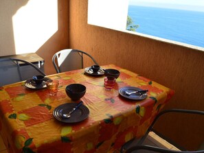 A table set with plates, bowls, and glasses, overlooking a scenic view of the sea. - Studio cabin Banyuls 4 pers, sea view, parking, WiFi (Banyuls-sur-Mer)