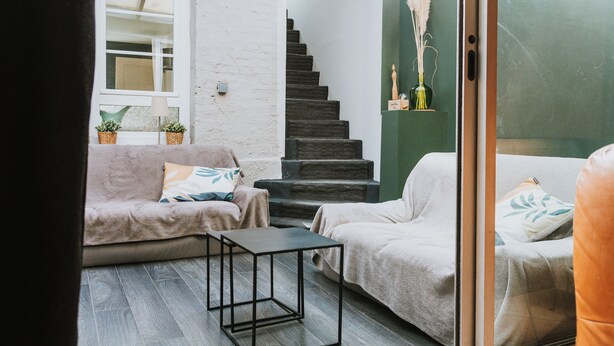 A modern living room with a sofa, a small table, and a staircase.