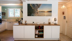 Una cocina moderna con una isla de madera, un cuadro grande de una ola y vistas al océano.
