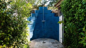 Un muro de ladrillo azul con una reja metálica y un camino de piedra que conduce a él.