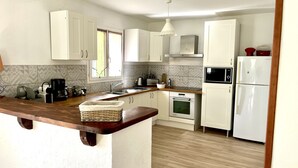 Una cocina moderna con armarios blancos, encimera de madera, horno empotrado, microondas y fregadero.