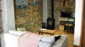 A cozy living room with a stone wall, a fireplace, a sofa, and artwork. - Corsican charming house  (Brando)