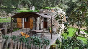 A rustic outdoor seating area with stone walls, wooden doors, and a covered patio. - Corsican charming house  (Brando)