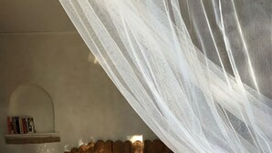 A bed with a canopy, a bedside lamp, and a shelf with books. - Corsican charming house  (Brando)