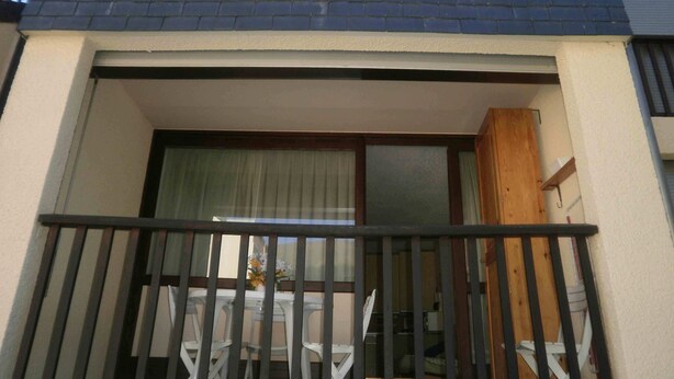 Ein Balkon mit schwarzem Geländer, einem weißen Tisch und weißen Stühlen.
