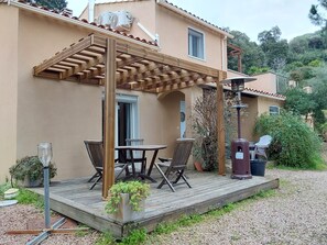 Un área de patio techada con una mesa, sillas, un bote de basura y una planta en maceta.