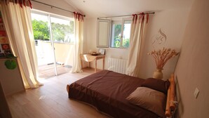 A bedroom with a large bed, a small desk, a radiator, and a window with curtains.