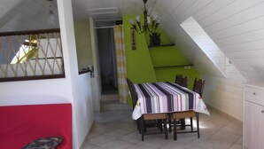 A dining area with a table covered by a striped tablecloth, a red couch, and a staircase leading to an upper level.