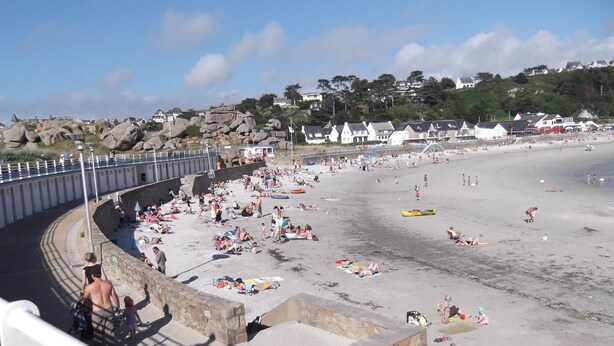 A beach with a stone wall and a promenade.