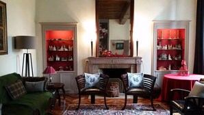A cozy living room with a fireplace, two armchairs, a green sofa, and a small table with a red tablecloth.