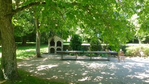 A park with a stone structure, a wooden bench, and a paved area.