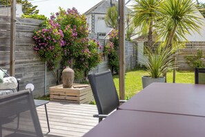 A patio area with a wooden deck, a table, chairs, and a potted plant. - Parenthèse idéale - Exceptional Villa in Carnac Panoramic Sea View (Carnac)