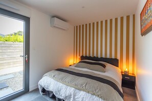 A bedroom with a bed, a window, and a wall-mounted air conditioner. - Parenthèse idéale - Exceptional Villa in Carnac Panoramic Sea View (Carnac)