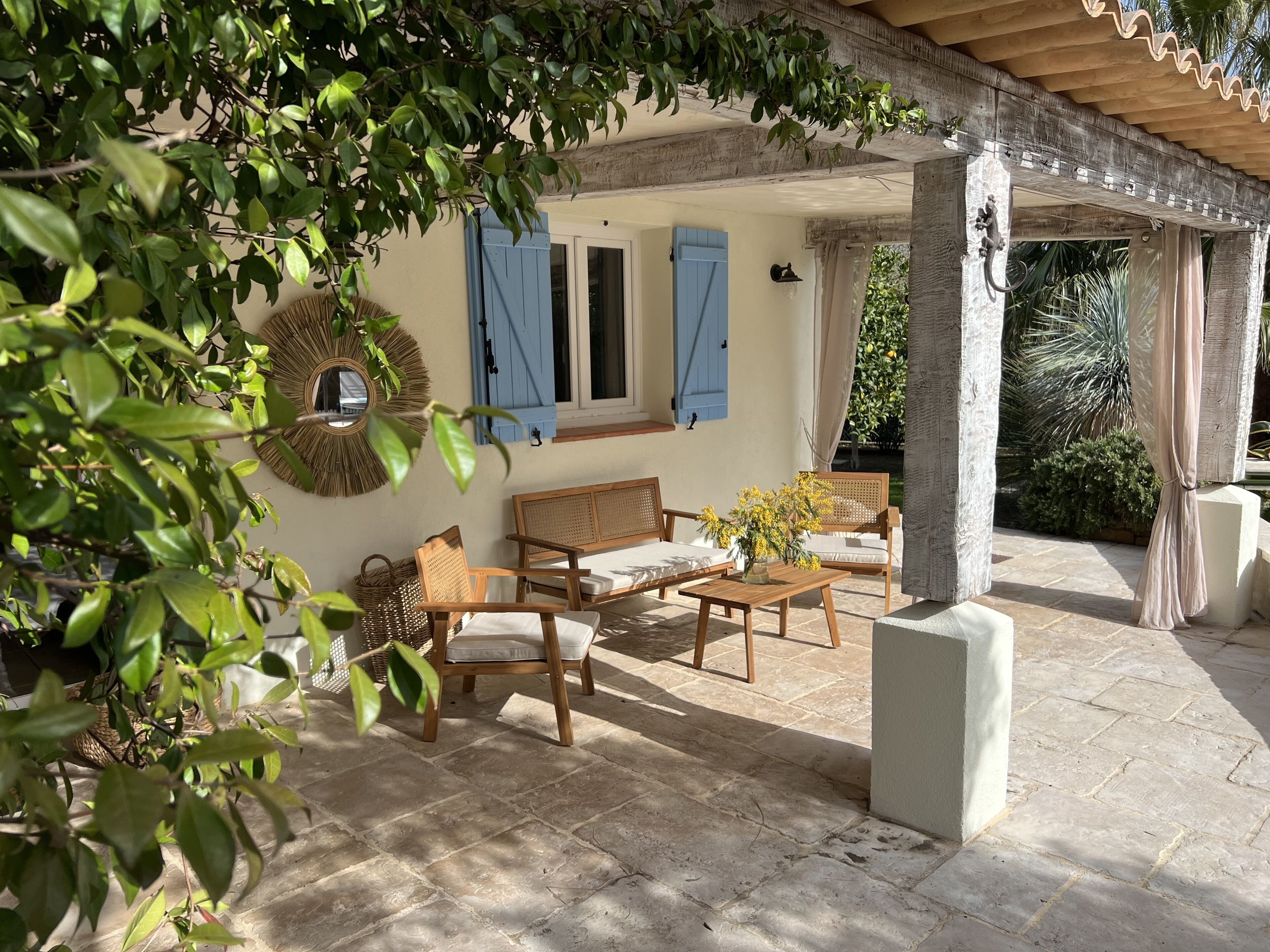A covered outdoor seating area with wooden furniture and a wicker chair.