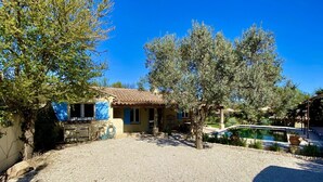 Una villa con techo de tejas, piscina y camino de entrada de grava.