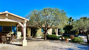 Un patio con pérgola, mobiliario exterior y un árbol grande.