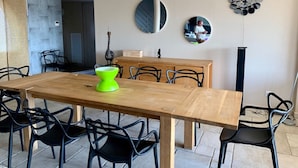 Uma área de refeições com mesa de madeira e cadeiras pretas, um armário de madeira e dois espelhos redondos na parede.