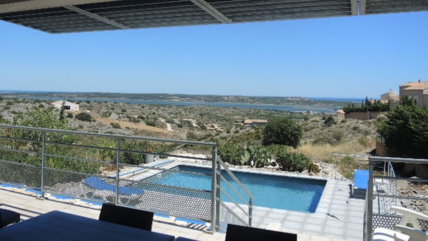 Uma área de piscina com vista para o mar e paisagem distante.