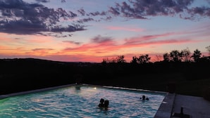Una piscina al tramonto con due persone nell'acqua.