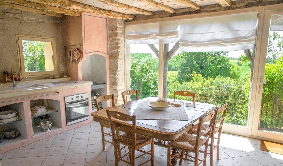 Una cucina rustica con zona pranzo, ampie finestre e vista sul verde.