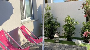 A patio with a large umbrella, a red chair, and a small table. - New air-conditioned T2/3 MINI loft near the paradisiacal beaches of the South Shore (Grosseto-Prugna)