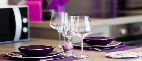 A dining table with purple placemats, clear wine glasses, and a purple bowl.