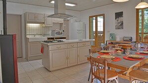 A kitchen with white cabinets, a gas stove, and a dining area with wooden chairs and a table set for four.