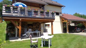 A two-story house with a balcony, a covered patio, and a garage. - House for rent in the Haut Jura (Longchaumois)