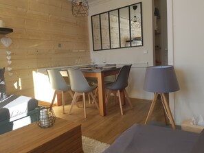A dining area with a wooden table, four chairs, and a modern pendant light. - Plagne Soleil Appart for 5 persons PIED DES PISTES /PLEIN SUD (Mâcot-la-Plagne)