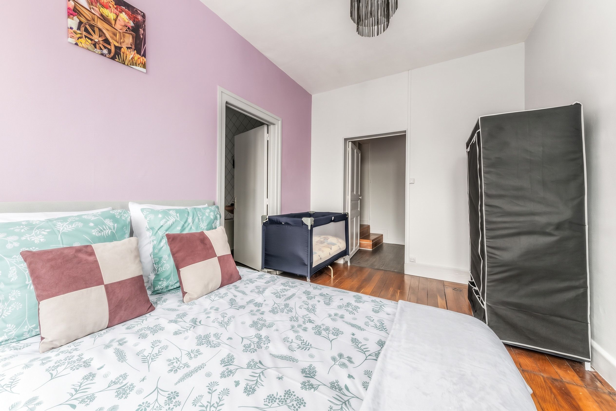 Une chambre à coucher comprenant un lit, une armoire et une porte donnant sur une autre pièce.
