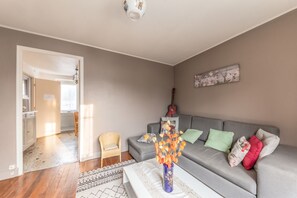 A living room with a grey sofa, a wicker chair, a vase with orange flowers, and a painting on the wall. - Homerez - House in Bourbon-Lancy (Bourbon-Lancy)