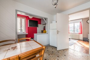 A compact kitchen with a dining area, a refrigerator, a microwave, and a window with curtains. - Homerez - House in Bourbon-Lancy (Bourbon-Lancy)