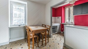 Una cucina compatta con zona pranzo, pavimento piastrellato, una finestra vista e parete di accento rossa.