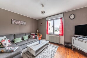 A modern living room with a grey sofa, a white coffee table, and a flat-screen TV.