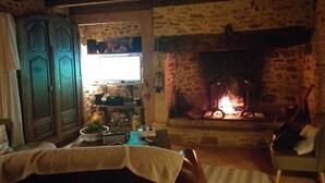Een gezellige woonkamer met een stenen open haard, houten meubels en een televisie op een stenen muur.