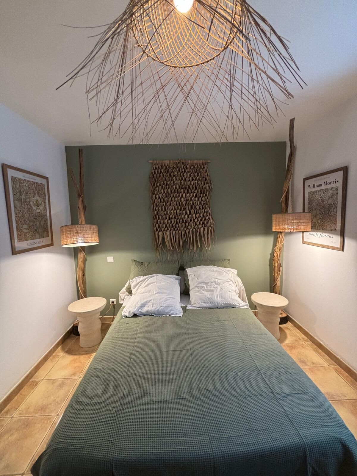 Een slaapkamer met een bed, twee nachtkastjes, een hanglamp en twee wandlampen.