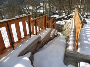 A wooden staircase with snow on the steps and railings, leading to a stone wall. - NEW: GERARDMER Mountain chalet 12 people (Gérardmer)