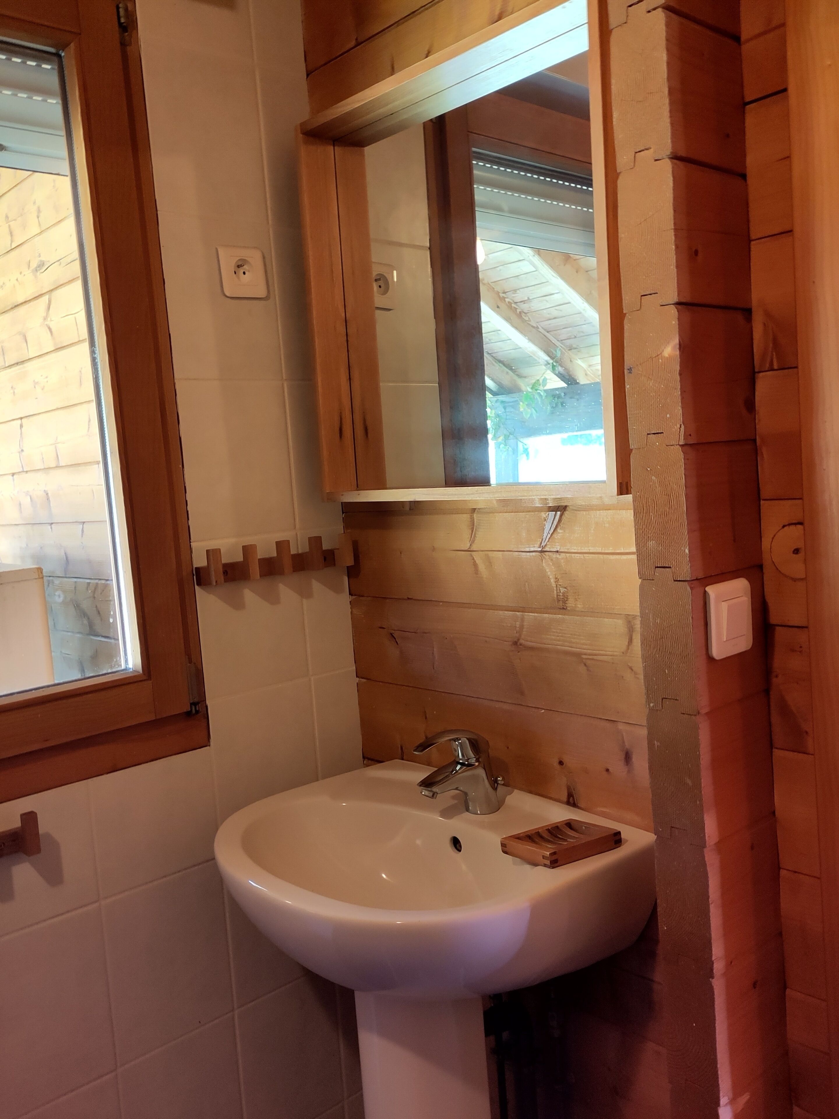 Un baño con pared de madera, un lavabo blanco y un espejo encima.
