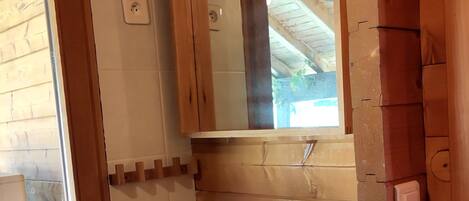 Un baño con pared de madera, un lavabo blanco y un espejo encima.