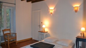 A bedroom with a bed, two bedside lamps, a chair, and a window with curtains. - Cottage with a pond on the border of Brittany and Normandy (La Baconnière)