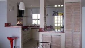 Een keuken met een eethoek, een fiets en een raam met luiken.