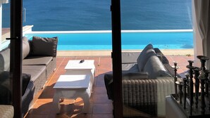 A room with a large glass door leading to a balcony with a view of the ocean. - Villa by the sea - Breathtaking sea view & infinity pool - Costa del Sol (manilva)