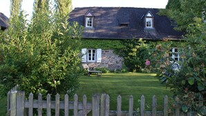 Et hus med en stenvæg og et træhegn.