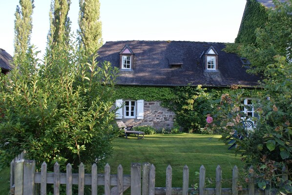 Une maison avec un mur en pierre et une clôture en bois.