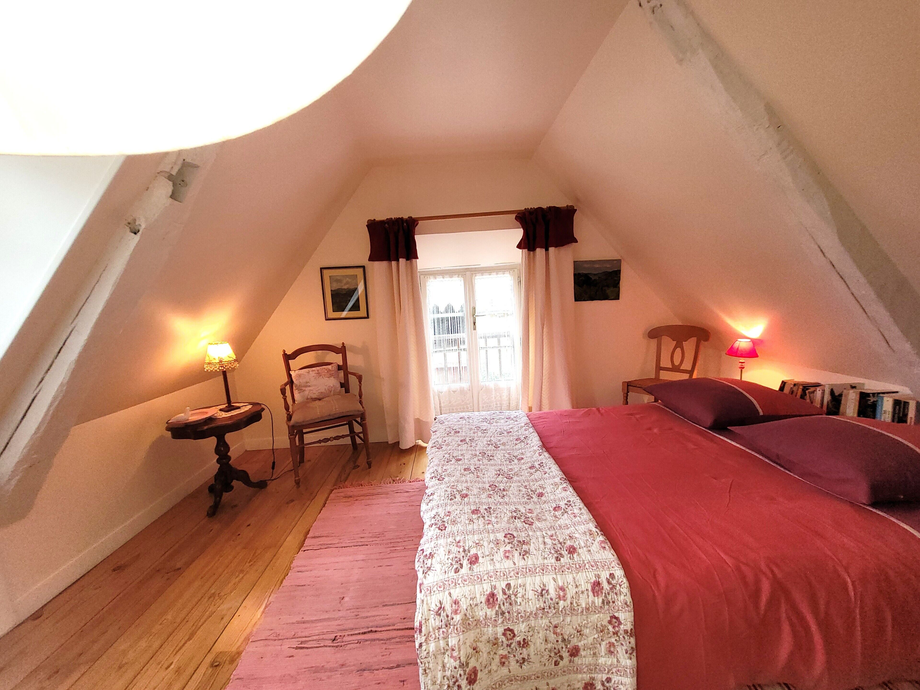 A bedroom with a bed, a chair, a table, and a lamp.