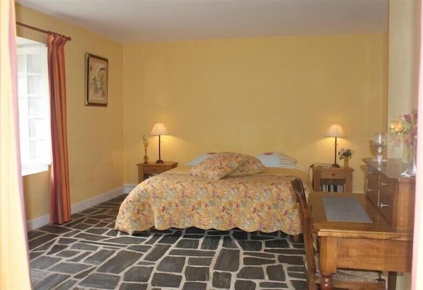 Une chambre comprenant un lit, deux tables de chevet avec des lampes, un bureau en bois et une chaise.