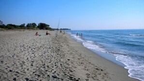 Una playa arenosa con huellas y algunas personas.