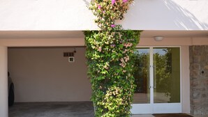A building with a garage door, a stone wall, and a vertical garden with flowers. - Ste Maxime, sea view Comfortable, quiet, walk to the town center and beaches (Sainte-Maxime)